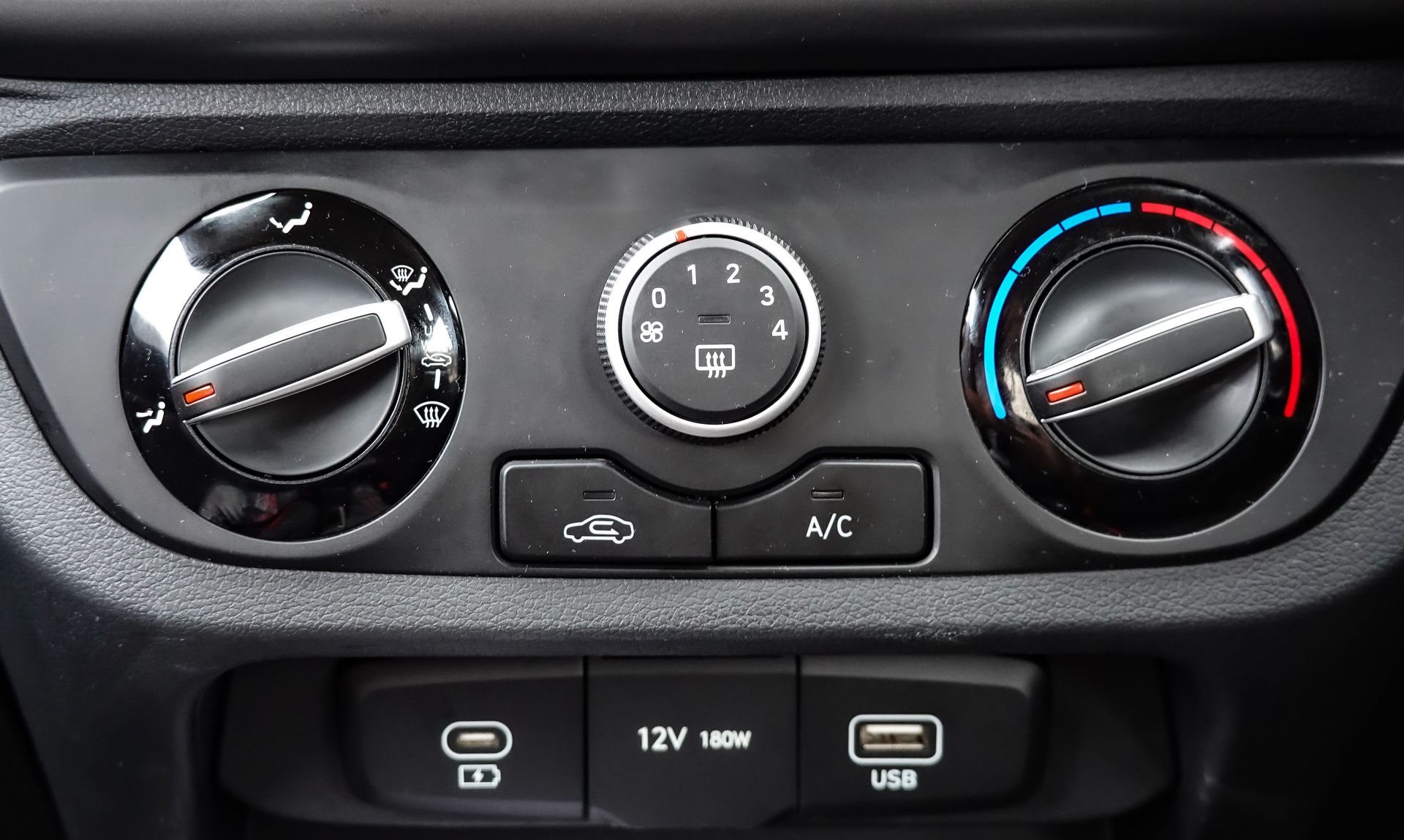 Close-up view of car air conditioning and dashboard controls, featuring climate settings and connectivity ports.